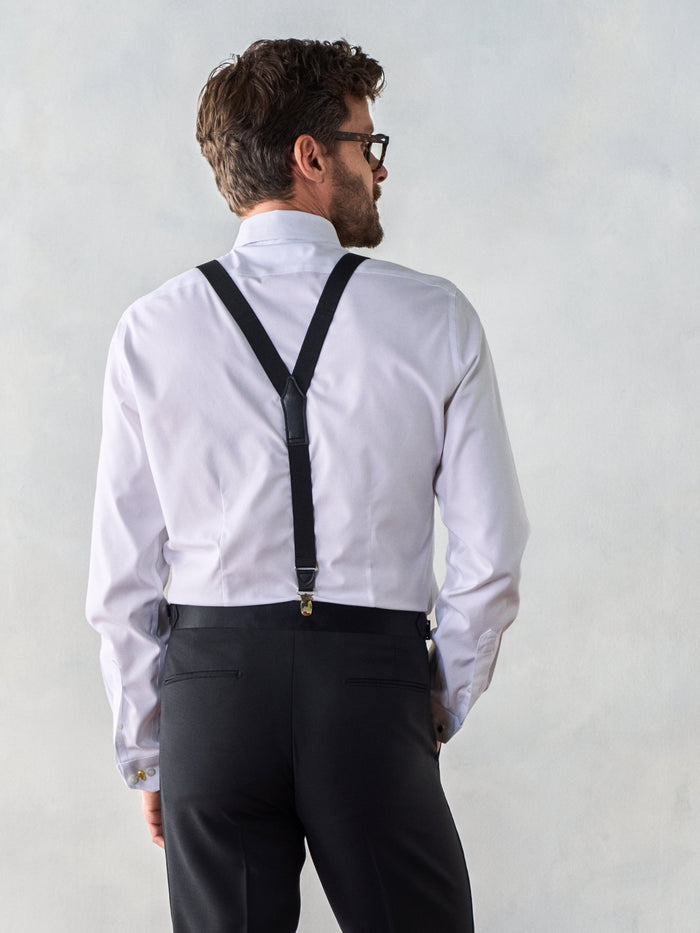 Man in white shirt with black gold-clip suspenders and black trousers, back view
