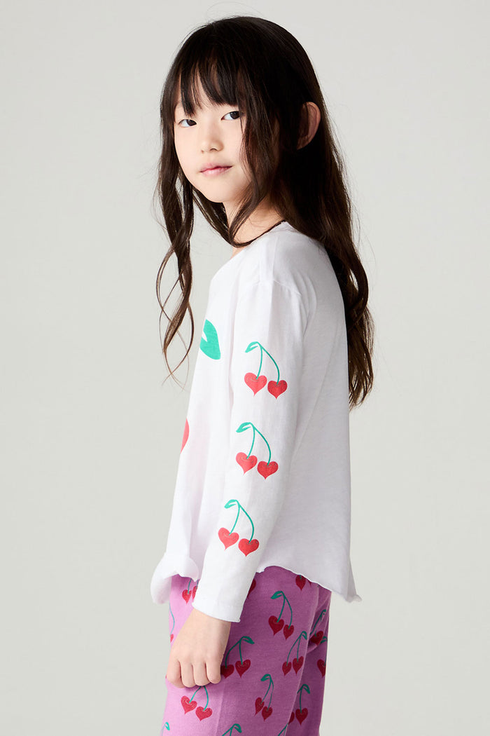 Side view of a girl wearing the Chaser Sweethearts Girls Tee on a neutral background with pink pants