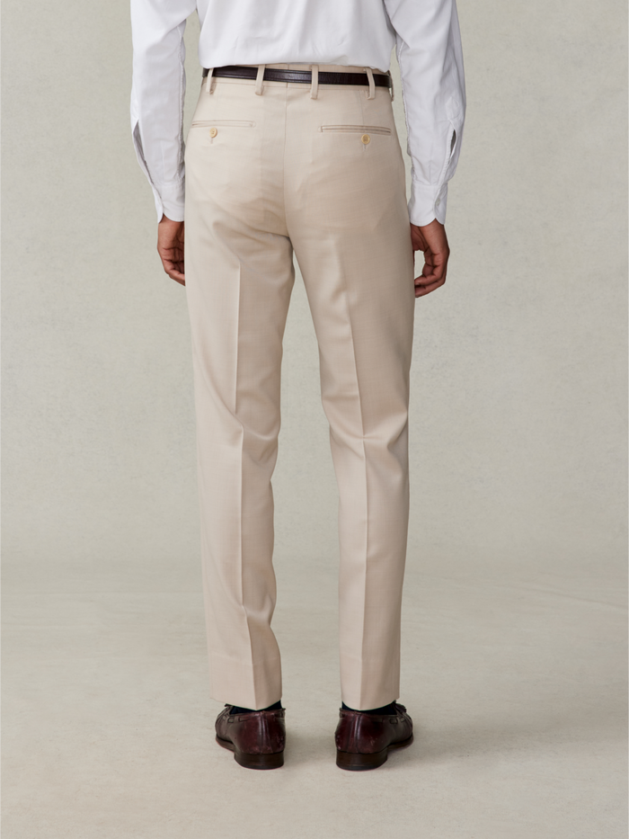 Back view of tan suit trousers on model in white shirt, waist-down view