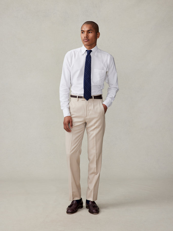 Man in white dress shirt, navy tie, and tan trousers, front full-body view