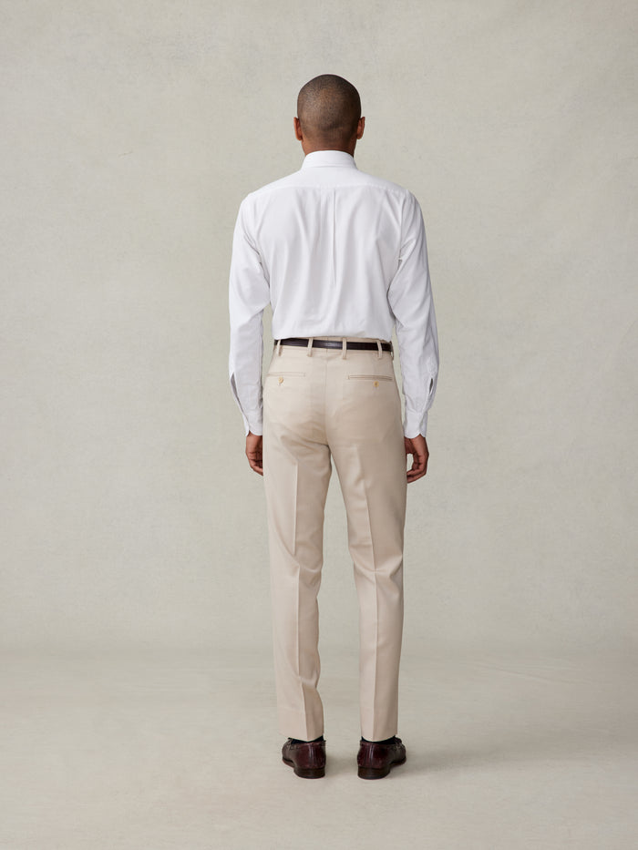 Back view of man in white dress shirt and tan trousers, full-body