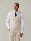 Man in tan suit vest, white shirt, and navy tie, front view, waist-up