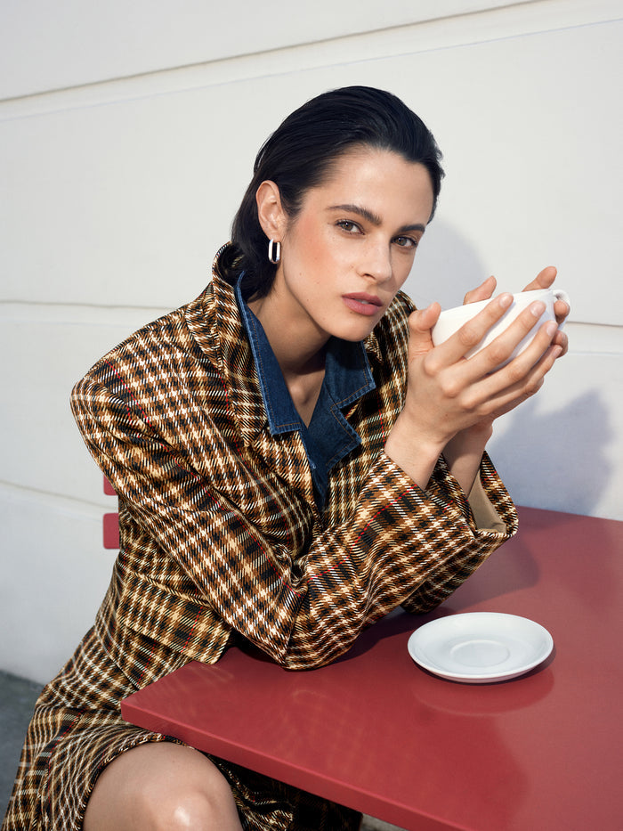 A woman wearing a heritage style checked blazer with long sleeves,button down fastening, pointed collar and a relaxed boxy fit.