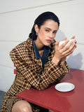 A woman wearing a heritage style checked blazer with long sleeves,button down fastening, pointed collar and a relaxed boxy fit.