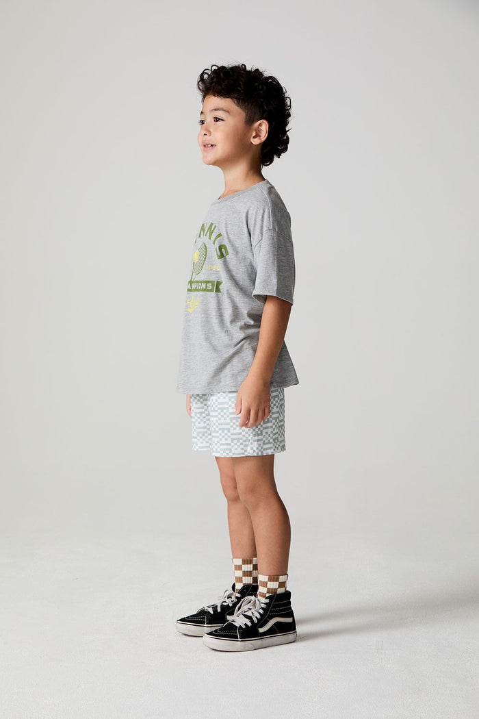 Full body side angle view of a boy wearing the Chaser Tennis Club Tee on a neutral background
