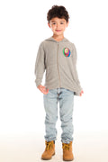 Full body view of boy wearing Chaser’s The Grateful Dead Colorblocked Stealie heather grey zip up hoodie with colorful Steal Your Face logo, light blue jeans, and brown boots on a white background