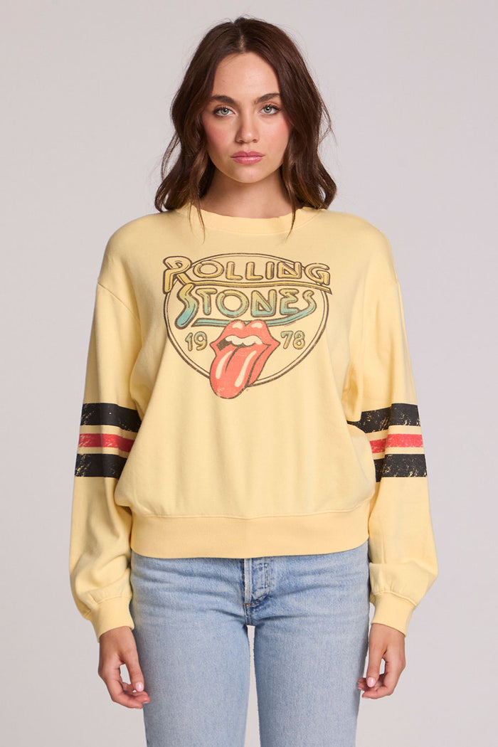 Front view of a woman wearing the Chaser  The Rolling Stones 1978 Long Sleeve Tee and jeans on a neutral background with arms lowered