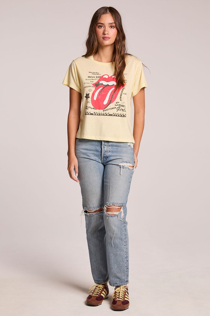 Full body front view of a woman wearing the Chaser  Rolling Stones Logo Magazine Mix Tee and sneakers on a neutral background with hands at her side