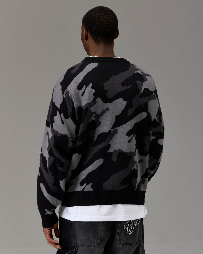 Person wearing a camouflage sweater with a plain background
