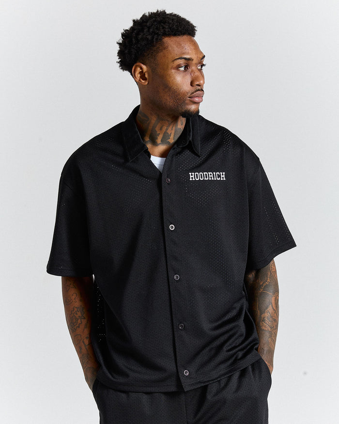 Man wearing a black 'HOODRICH' shirt on a white background