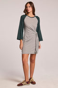 Front view of a woman wearing the Chaser  Thompson Streaky Grey and Pine Mini Dress on a neutral background with sneakers