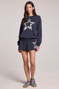 A full body front view of a woman wearing the Chaser Tie Dye Star Shorts  and long sleeve on a neutral background