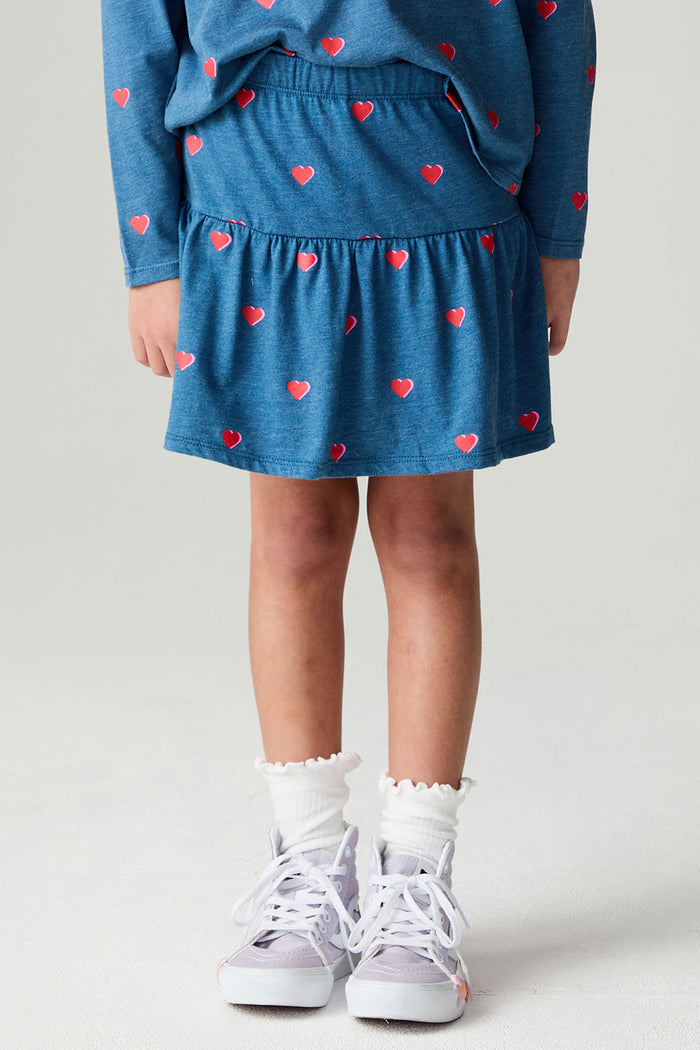 Front view of a girl wearing the Chaser Tiny Hearts Girls Skirt on a neutral background with arms lowered and matching shirt