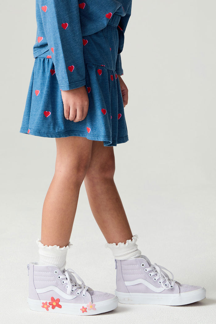 Side view of a girl wearing the Chaser Tiny Hearts Girls Skirt on a neutral background with arms lowered