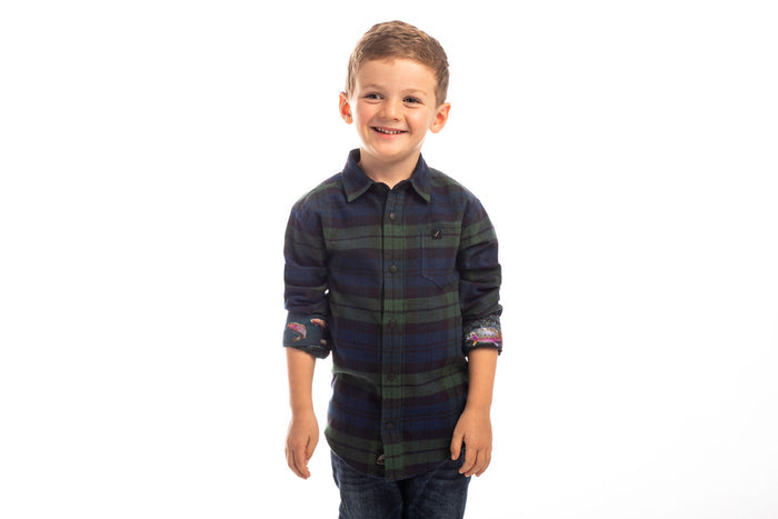 Smiling boy wears Pladra Toddler Cubs Flannel Shirt in Bolinas Blue, standing against a plain white backdrop.