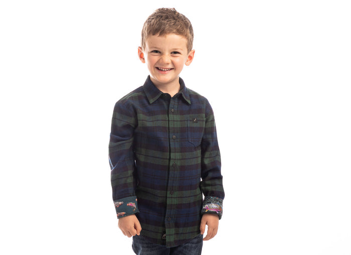 Smiling young boy wears the Pladra Toddler Cubs Flannel Shirt in Bolinas Blue, standing by a plain white background.