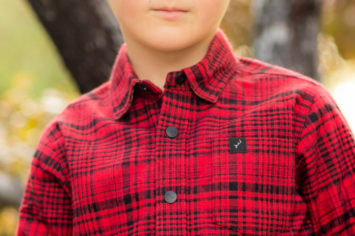 Toddler wears Pladra's Wrangler Red Cubs Flannel Shirt, standing outdoors with blurred trees in the background.