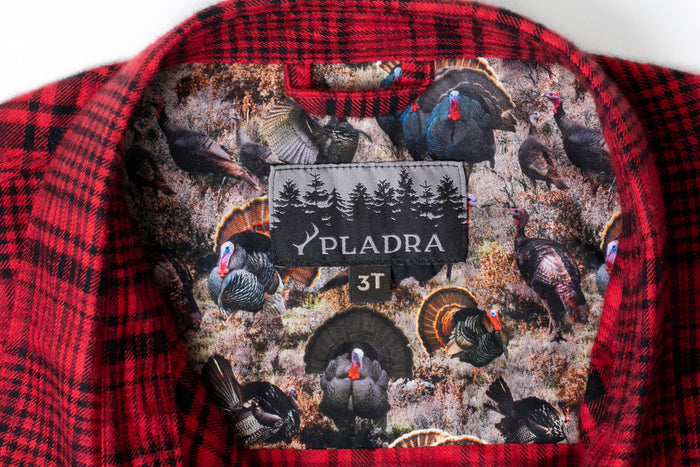 Close-up of the Pladra Toddler Cubs Flannel Shirt in Wrangler Red, showing collar with nature print liner and label.