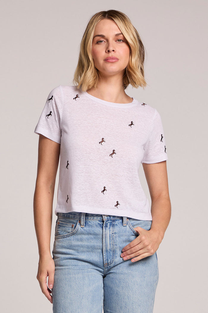Front view of a woman wearing the Chaser  Tossed Horses Tee and jeans on a neutral background