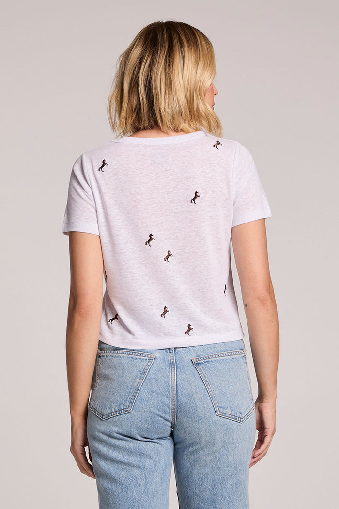 Back view of a woman wearing the Chaser  Tossed Horses Tee on a neutral background