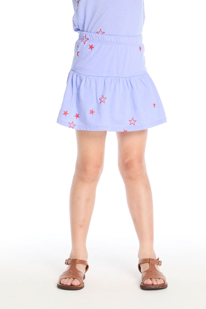 Girl wearing the Chaser Kids Tossed Stars Powder Blue Peplum Skort featuring scattered red star prints and a soft peplum hem