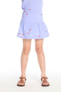 Girl wearing the Chaser Kids Tossed Stars Powder Blue Peplum Skort featuring scattered red star prints and a soft peplum hem