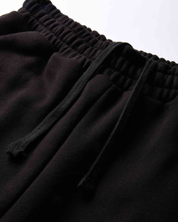 Close-up of black pants with a drawstring waistband on a light gray background
