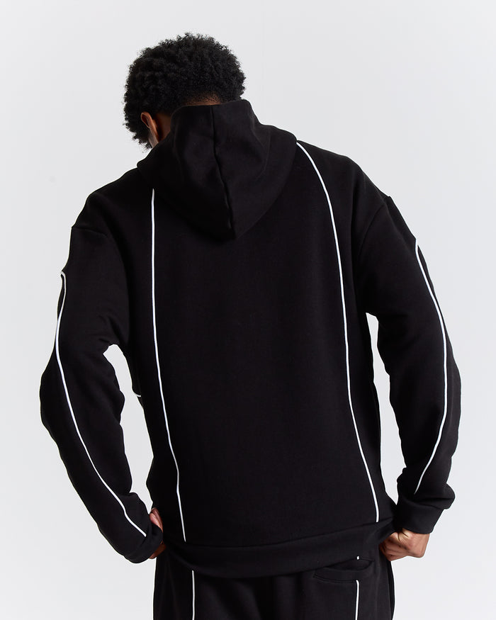 Person wearing a black hoodie with white accents on a light gray background