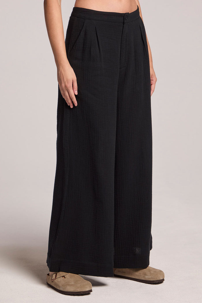 Side angle view of a woman wearing the Chaser True Black Campaniaa Trousers on a neutral background