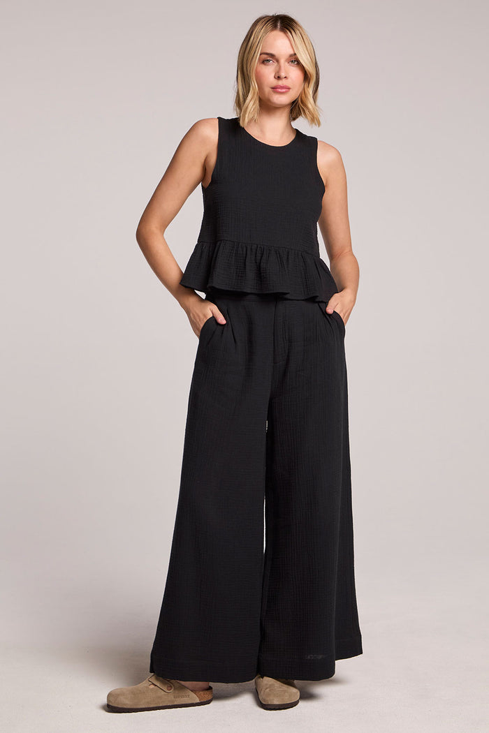 Front  full view of a woman wearing a black Chaser Liberty tank set, pants, and slides on a neutral background