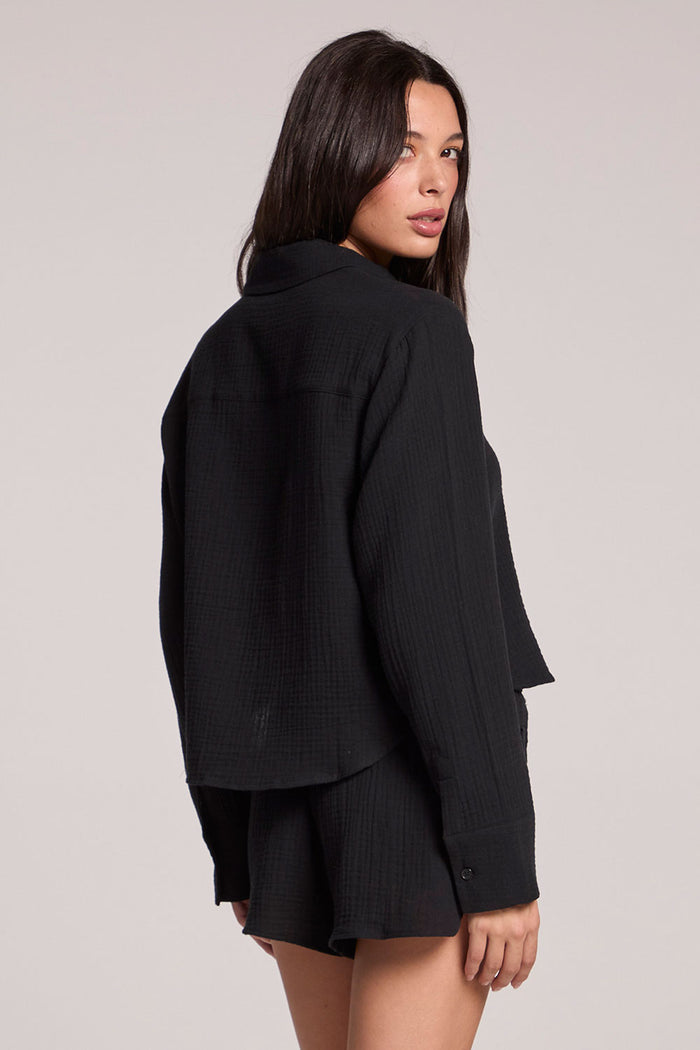 Back view of a woman wearing the Chaser Paso long sleeve in true black on a neutral background