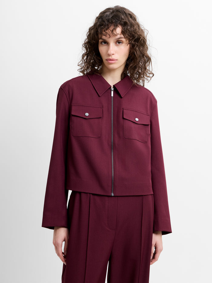 Woman wearing a burgundy collared jacket with matching burgundy trousers