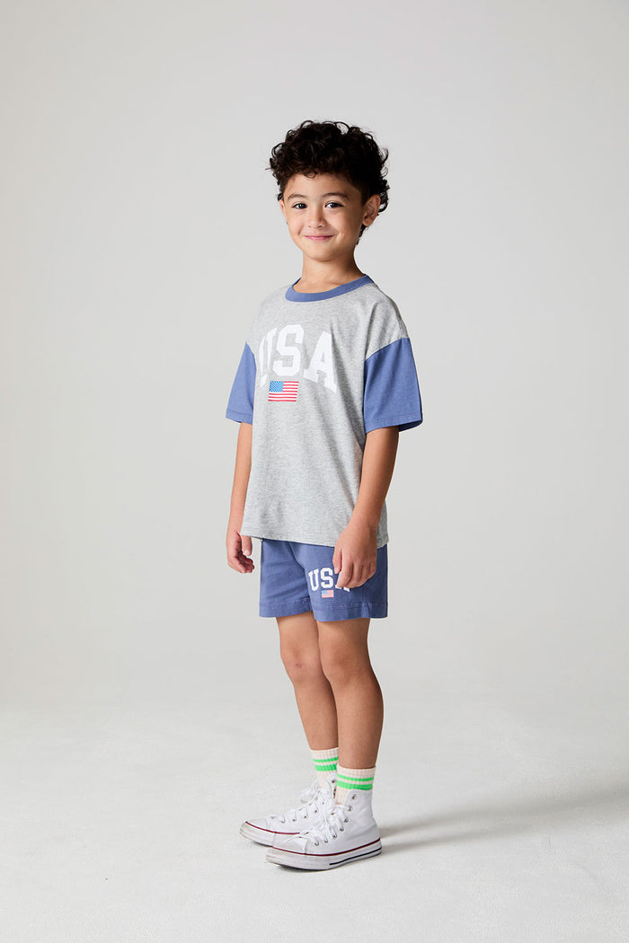Full body side view of a boy wearing the Chaser U.S.A. Flag Shorts on a neutral background