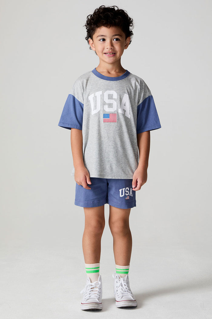 Full body side view of a boy wearing the Chaser U.S.A. Flag Tee and shorts on a neutral background