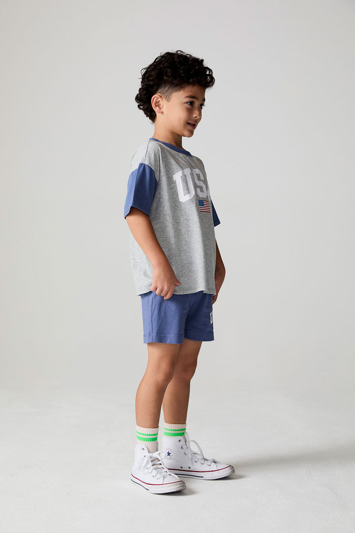 Full body side view of a boy wearing the Chaser U.S.A. Flag Tee on a neutral background