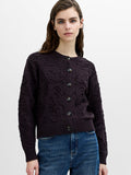 A woman wearing a dark brown 3D box fit, floral knit cardigan with button through fastening, a ribbed crew neck and long sleeves.