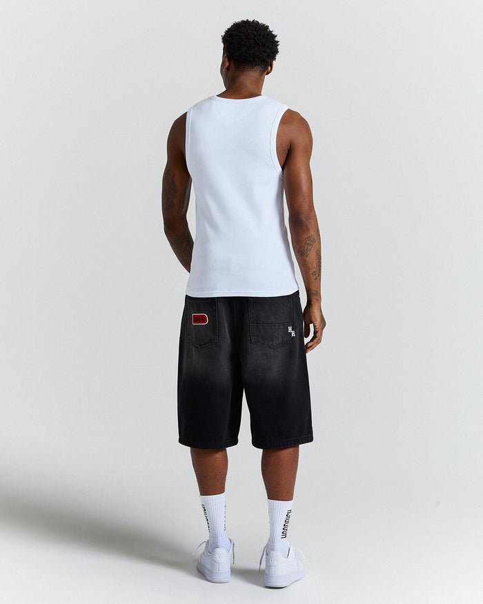 Person wearing a white tank top and black shorts on a light gray background