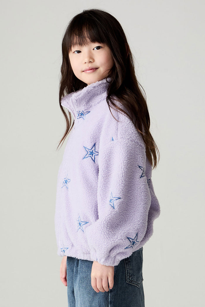 Side view of a girl wearing the Chaser Varsity Stars Girls Varsity Jacket on a neutral background with jeans looking at camera