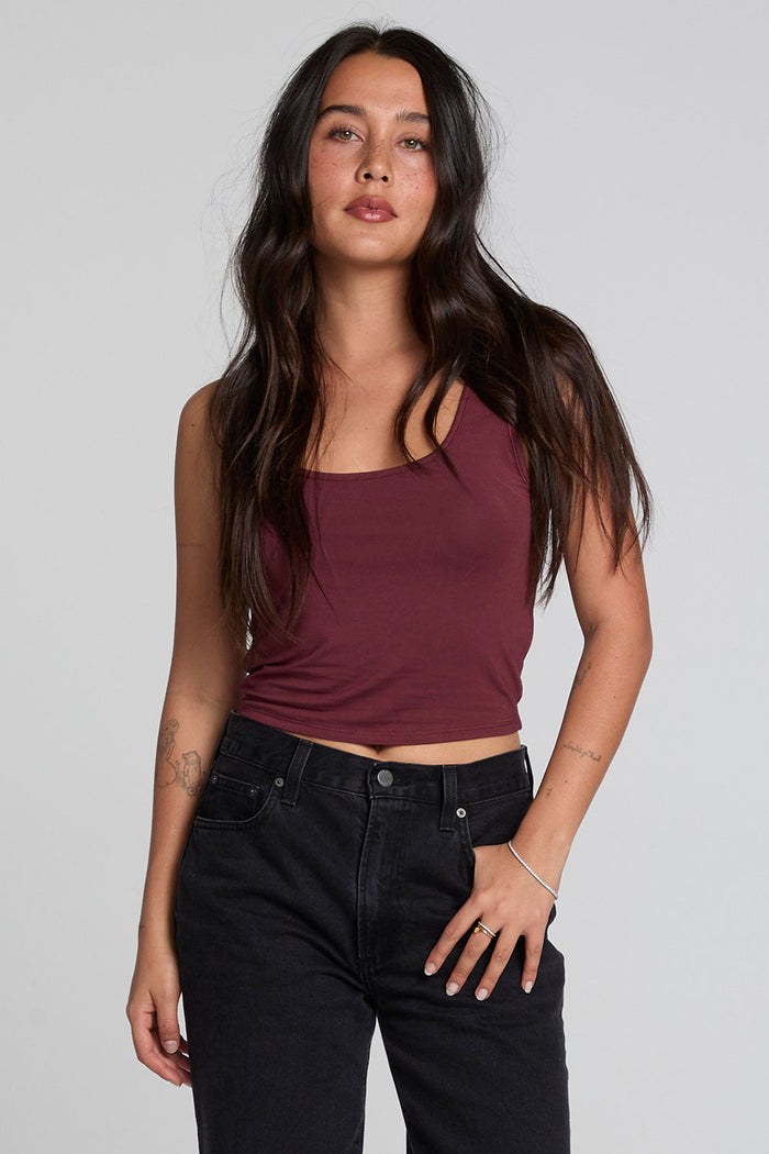 Front view of a woman wearing the Chaser Verze Brick Tank and high waisted jeans on a neutral background