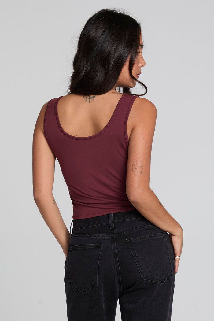 Back view of a tattooed woman wearing the Chaser Verze Brick Tank and jeans on a neutral background