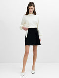 A woman wearing a tailored high-waisted black mini skirt with pleat detailing.