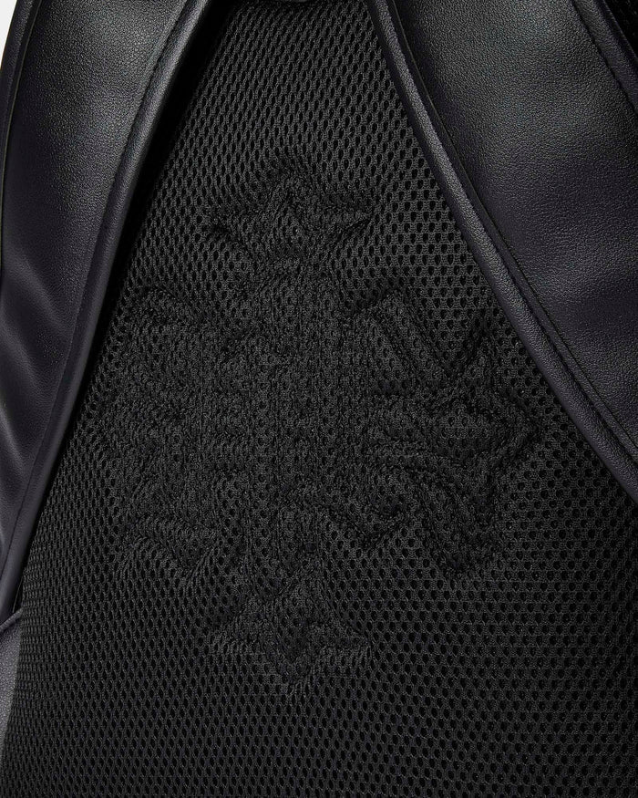 Close-up of a black leather product with a brand logo on a textured surface.