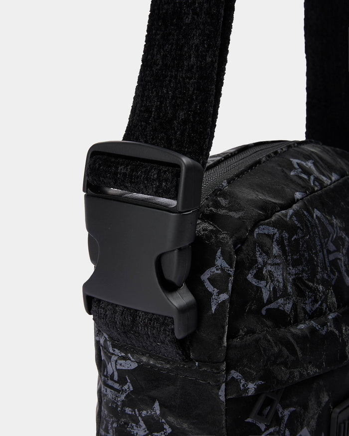 Close-up of a black patterned bag with a buckle on a light gray background