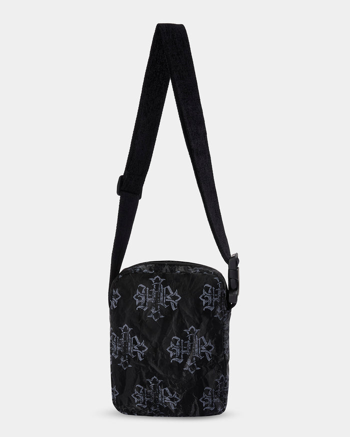 Black patterned crossbody bag on a light gray background