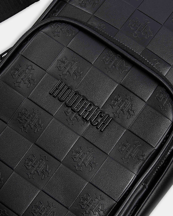 Close-up of a black leather product with 'HOODRICH' branding and quilted pattern.