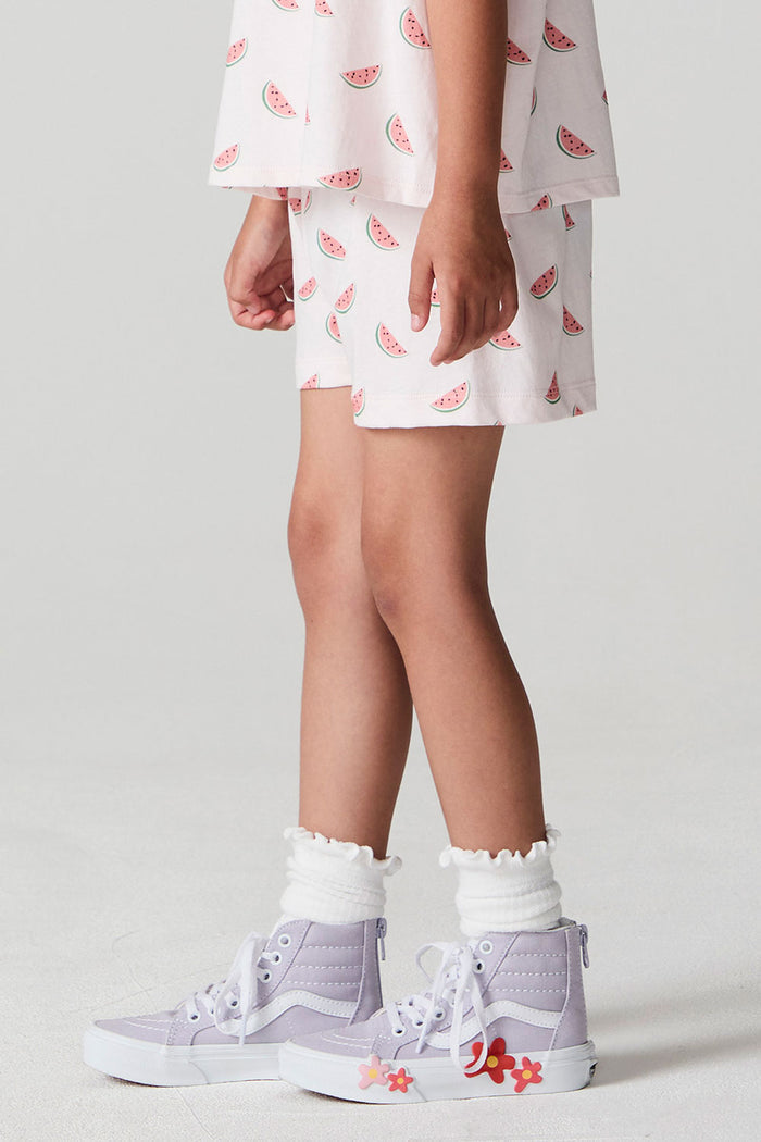 Side view of a girl wearing the Chaser Watermelon All Over Shorts  on a neutral background