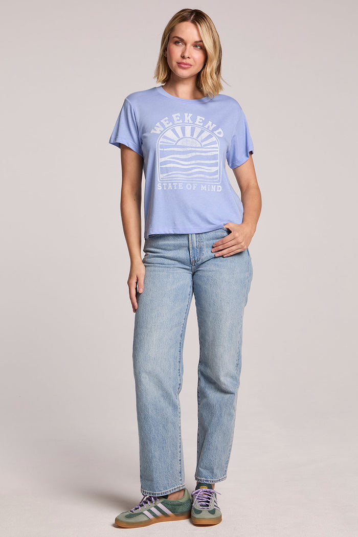 Front view of a woman wearing the Chaser  Weekend State Of Mind Tee and sneakers on a neutral background