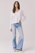 Full body view of woman wearing Chaser’s Whiskey White Long Sleeve paired with blue jeans on a plain background