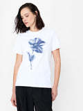 A woman wearing a soft cotton white T-shirt with a blurred graphic flower, a crew neck and short sleeves.