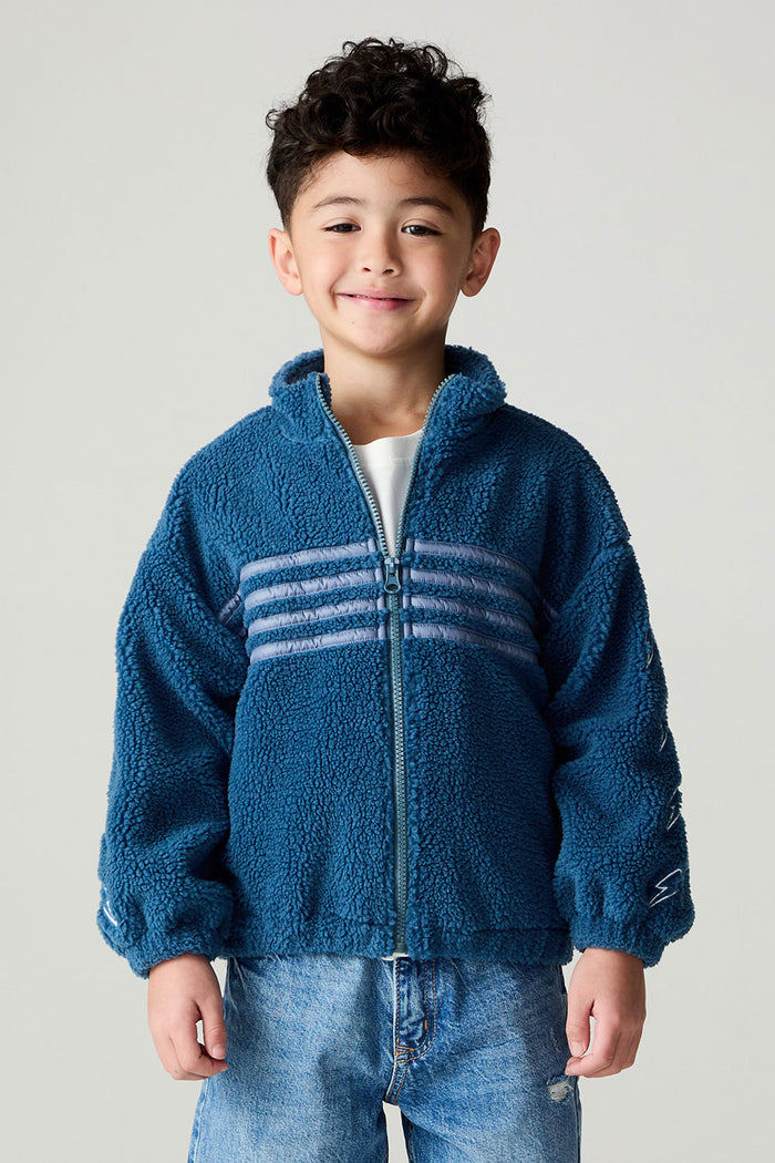 Frontview of a boy wearing the Chaser White Bolts Boys Jacket and bluejeans on a neutral background